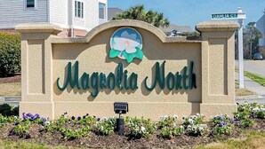 Señal de Magnolia North con un logotipo, señal de calle para Dahlia Ct y una luz alimentada por energía solar.