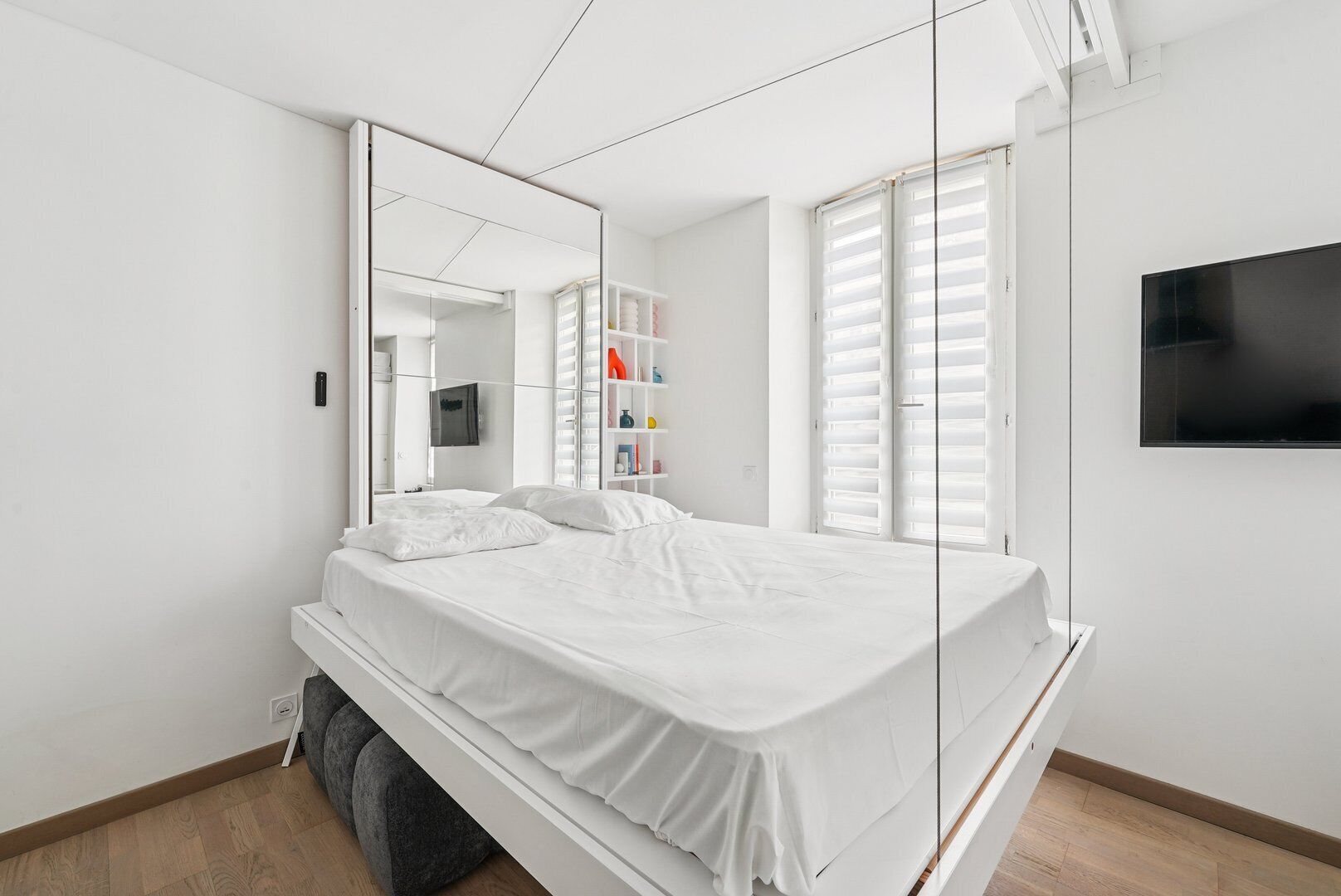 Une chambre moderne avec un grand lit, une armoire, un téléviseur et une fenêtre équipée de stores.