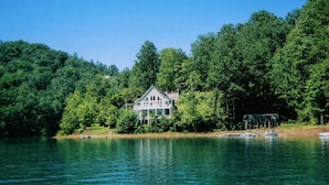 Una casa junto a un lago rodeada de un bosque denso.