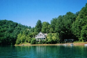 Ein Haus am See, umgeben von dichtem Wald.