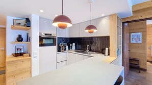 Une cuisine moderne dotée d’un îlot central, de luminaires suspendus et de meubles de rangement en bois.