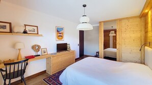 Une chambre à coucher comprenant un lit, un bureau, une chaise et une armoire en bois.