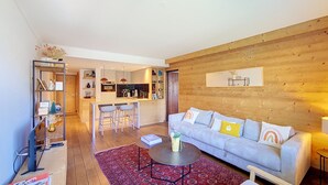 Un salon moderne avec un canapé, une table basse et un coin cuisine à l’arrière-plan.