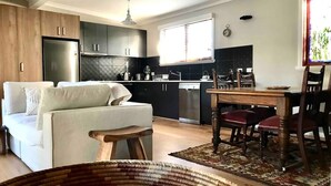 Una cocina moderna con armarios oscuros, horno empotrado y una ventana sobre el fregadero.