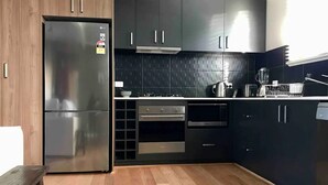 Una cocina moderna con armarios oscuros, un refrigerador de acero inoxidable, una estufa a gas y un microondas.