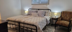 Une chambre à coucher avec un lit, deux lampes de chevet, une chaise et une table de nuit.