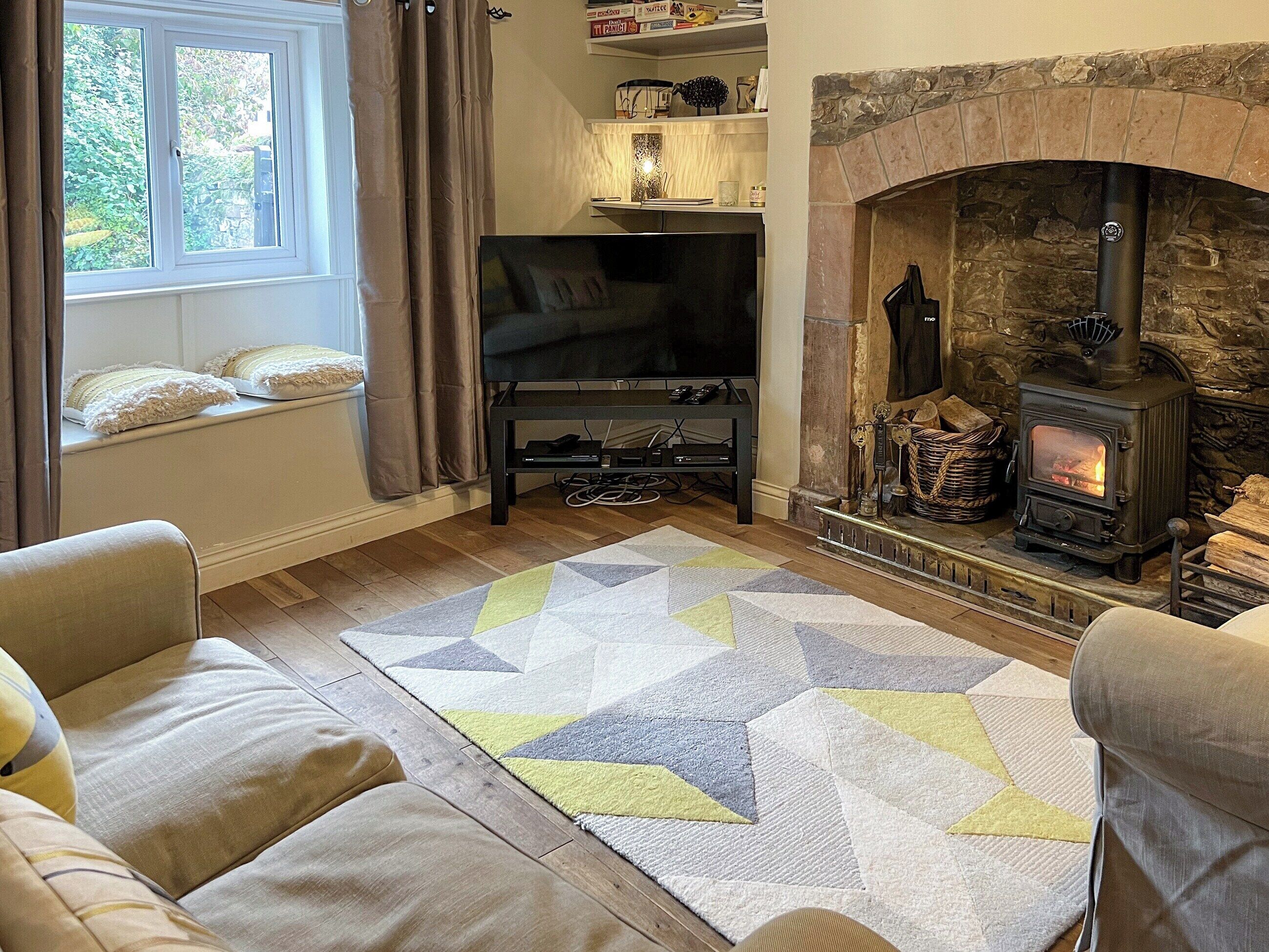 A cozy living room with a stone fireplace, a television, and comfortable seating.