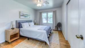 A bedroom with a bed, nightstand, lamp, ceiling fan, window with curtains, and a chair. - Charming  updated home in Midtown (Tulsa)