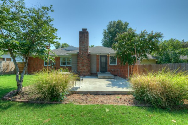 A two-story brick house with a chimney, a front porch, and a well-maintained lawn. - Charming mid century modern home in Midtown (Tulsa)