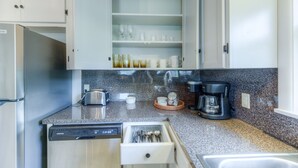 Eine Küche mit Geschirrspüler, Kaffeemaschine und einer Schubladeneinsatz.