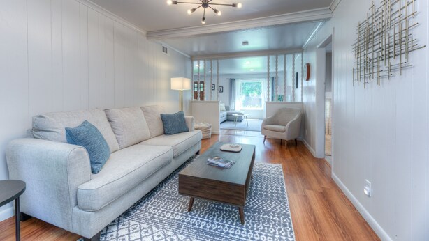 A modern living room with a sofa, coffee table, and a patterned rug. - Charming  updated home in Midtown (Tulsa)