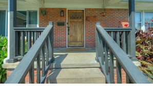 A front porch with a wooden door, a mailbox, and a hanging planter. - Charming  updated home in Midtown (Tulsa)