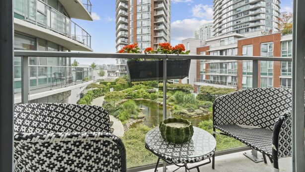 A balcony with two patterned chairs, a small table, and a hanging planter with flowers. - The Pond - The Full Package (Vancouver)