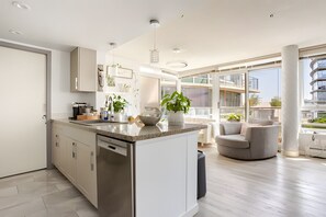 A modern kitchen with a central island, built-in appliances, and a large window offering a view of the city.