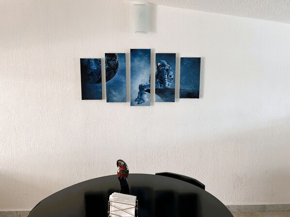 Una pared con cinco obras de arte enmarcadas que representan temas espaciales.