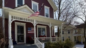 A two-story house with a porch, steps, and an American flag. - Renovated Victorian in 'Americas Coolest Small Town' (Hammondsport)