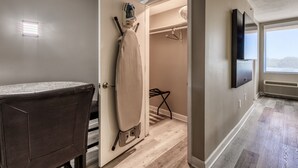 Ein modernes Zimmer mit integriertem Bügelbrett, einem wandmontierten Flachbildfernseher und Blick ins Freie durch ein großes Fenster.