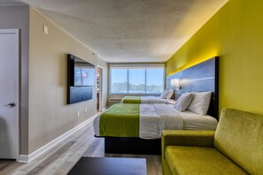 A hotel room with a large bed, a green sofa, a flat-screen TV, and a window with a city view. - Hotel Weston (Marietta)