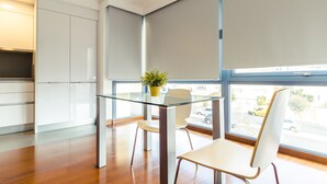 Uma cozinha moderna com armários brancos, uma mesa de vidro e uma planta em vaso.
