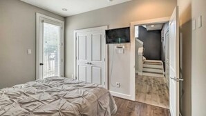 A bedroom with a bed, a door, and a television mounted on the wall. - NEW! Stylish Houston Townhome ~ 3 Mi to Downtown! (Houston)