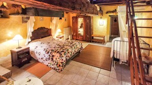 Een gezellige slaapkamer met een bed, nachtkastje, lamp en een houten bankje.