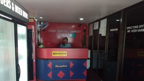 A reception area with a red and blue reception desk labeled "NADI AIRPORT TRANSIT HOTEL." - Nadi Airport Transit Hotel (Nadi)