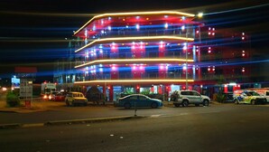 A multi-story building with illuminated balconies and a parking lot with several cars. - Nadi Airport Transit Hotel (Nadi)