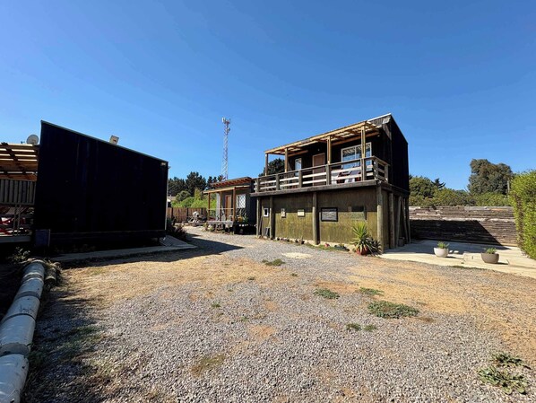 A two-story building with a balcony, a gravel driveway, and a satellite dish.