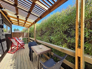 Une terrasse en bois avec une pergola, un espace salon extérieur et une vue sur un jardin.