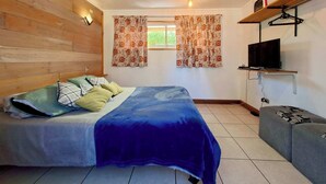 A bedroom with a bed, a TV mounted on a shelf, and a window with curtains. - Wheelchair-Friendly Cabin - BBQ, Parking & Wifi (Quintay)