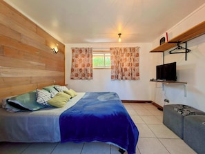 A bedroom with a bed, a TV mounted on a shelf, and a window with curtains. - Wheelchair-Friendly Cabin - BBQ, Parking & Wifi (Quintay)