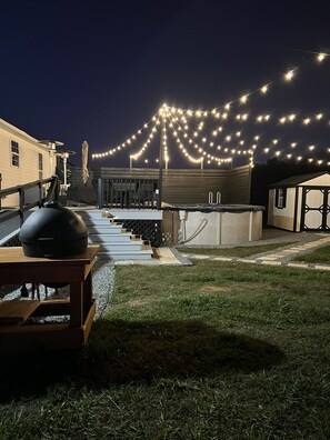 A rooftop patio with a barbecue grill, outdoor seating, and string lights.