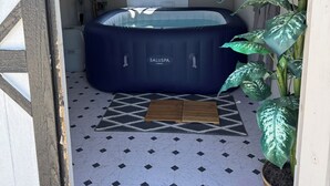 Une pièce avec un jacuzzi, une plante en pot et une porte avec une fenêtre.