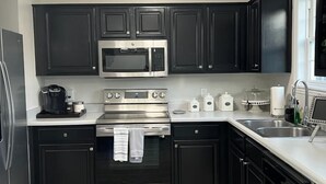 Une cuisine moderne avec des meubles de couleur sombre, des appareils en acier inoxydable et un plan de travail de couleur claire.