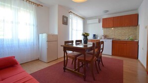 A compact living space with a dining area, kitchenette, and a red sofa. - Apartment Fejer 1 with balcony (Njivice)