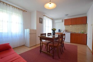 A compact living space with a dining area, kitchenette, and a red sofa.