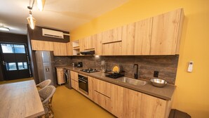Une cuisine moderne avec des meubles en bois, un réfrigérateur en acier inoxydable, un évier et un coin repas comprenant une table et des chaises.