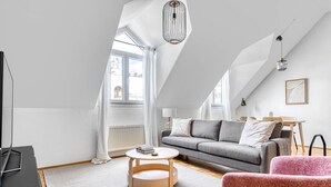 A modern loft apartment with a high ceiling, a grey sofa, a pink chair, and a round wooden coffee table. - Historic Margareten 2BR w/ Elevator in central location, by Blueground (Vienna)