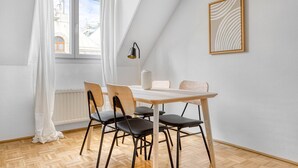 A dining area with a table and chairs, a radiator, a window with curtains, and a framed artwork on the wall. - Historic Margareten 2BR w/ Elevator in central location, by Blueground (Vienna)