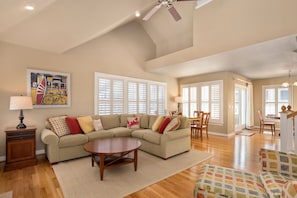 A spacious living room with a sectional sofa, a round coffee table, and a dining area with chairs.