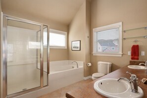 A bathroom with a glass-enclosed shower, a bathtub, a toilet, and a sink with a mirror.