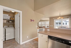 A kitchen with a dishwasher, a laundry area with dryers, and a sign indicating a direction.