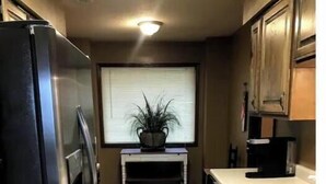 Eine Küche mit Kühlschrank, Kaffeemaschine und einem Fenster mit Jalousien.