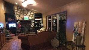 Ein gemütliches Wohnzimmer mit Kamin, Holzboden und Fernseher.