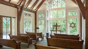 Ein Kircheninneres mit Holzbänken, großen Fenstern und einem Davidstern an einer Wand.