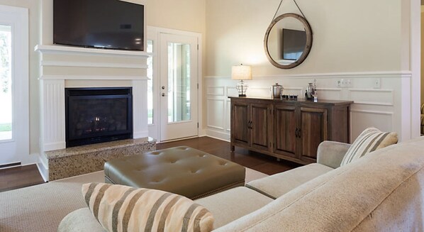 A living room with a fireplace, a television, a wooden cabinet, and a sofa.