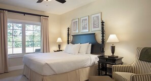 A hotel room with a large bed, two bedside tables with lamps, a chair, and a window with curtains.