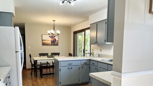 A modern kitchen with grey cabinets, a white countertop, and a dining area with a table and chairs. - Countryside Home, Dog Friendly, Large Yard, Near Several Lakes (Alexandria)