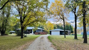 A gravel driveway leading to a house with a garage, surrounded by trees with yellow leaves. - Countryside Home, Dog Friendly, Large Yard, Near Several Lakes (Alexandria)