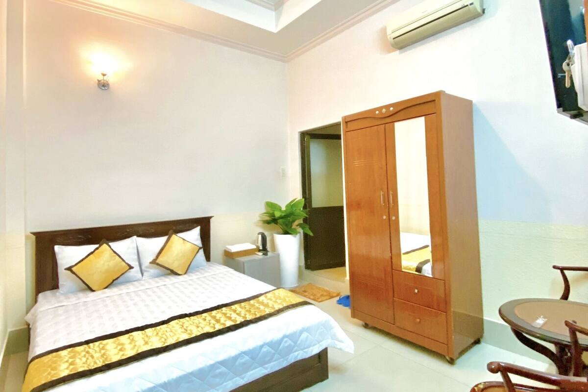 A bedroom with a bed, a wardrobe, a desk, and a chair.